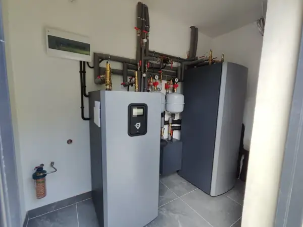 Profesjonalny montaż pompy ciepła. Widoczny zbiornik, instalacja hydrauliczna i rozdzielnica elektryczna.