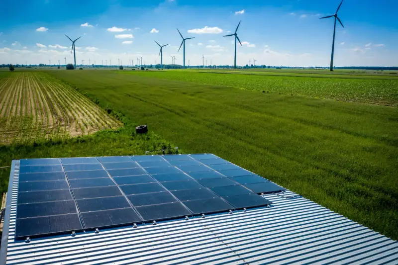 Panele słoneczne na dachu i wiatraki na polu, symbolizujące program agroenergia i zrównoważony rozwój.